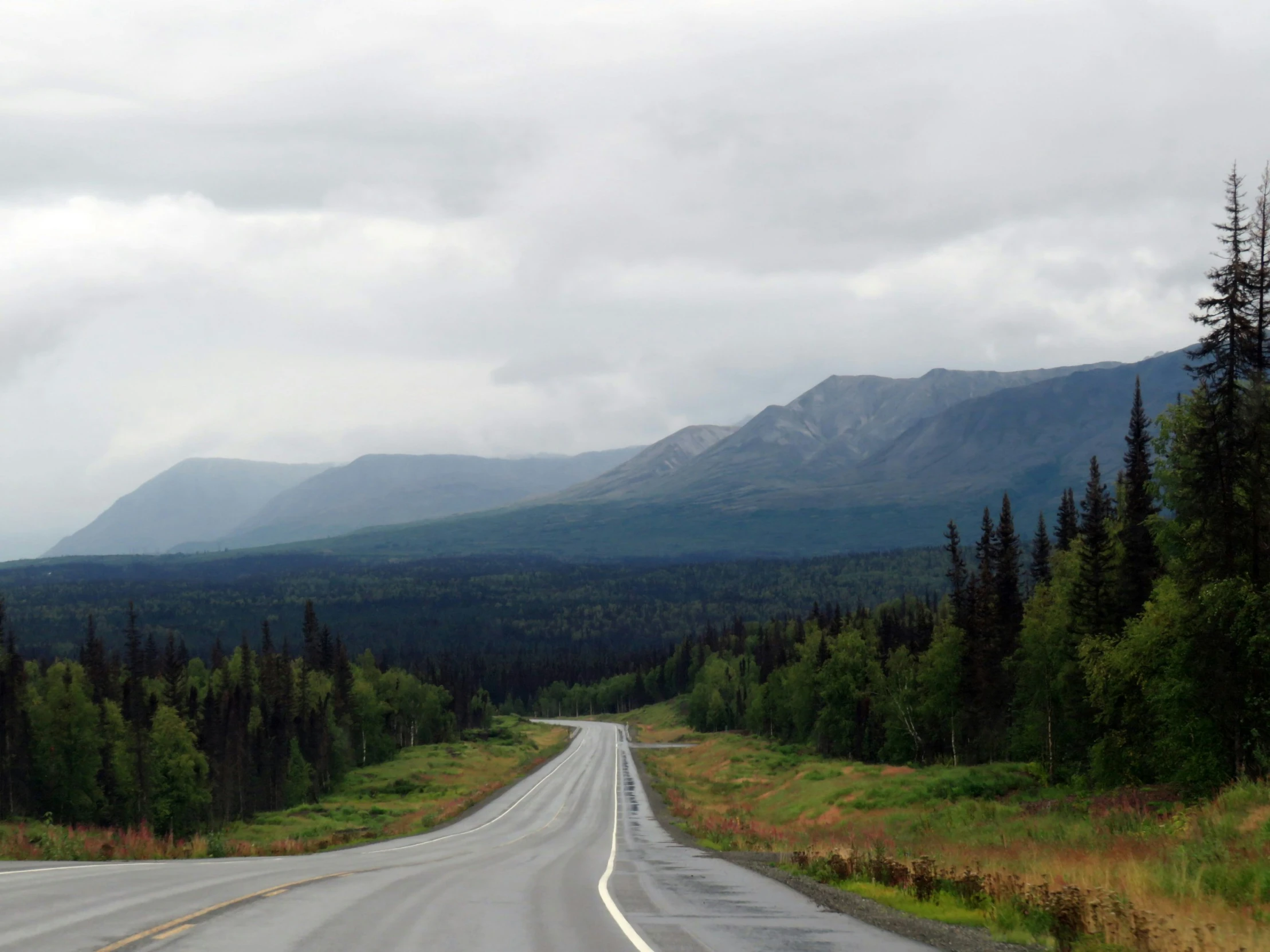 long, straight road surrounded by trees and mountains