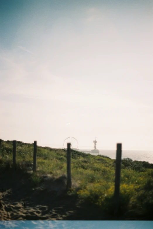 an empty pool next to a fenced in field with the ocean in the background