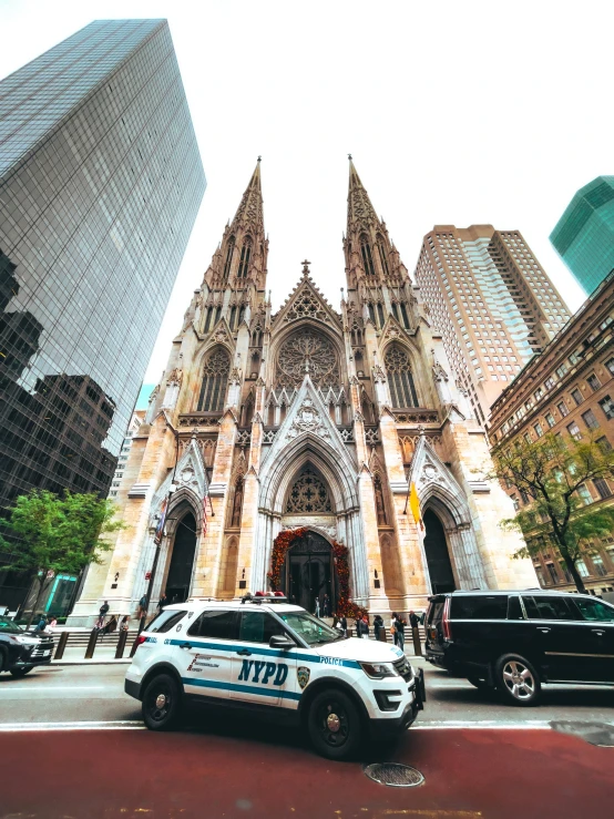 a very tall gothic type church with a police car