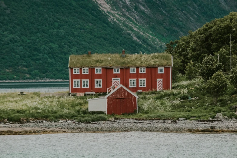 a red building with a grass roof next to some water