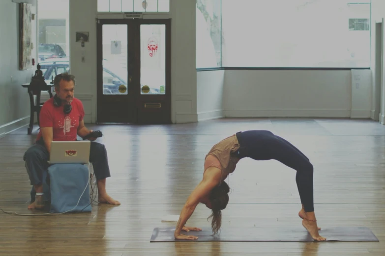 a woman performing a yoga pose while two men look on