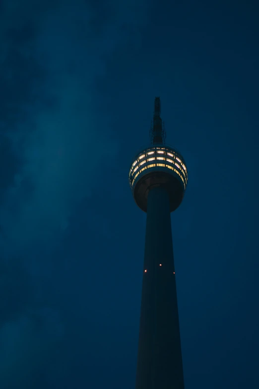 a light up tower lit at night with a cloudy sky