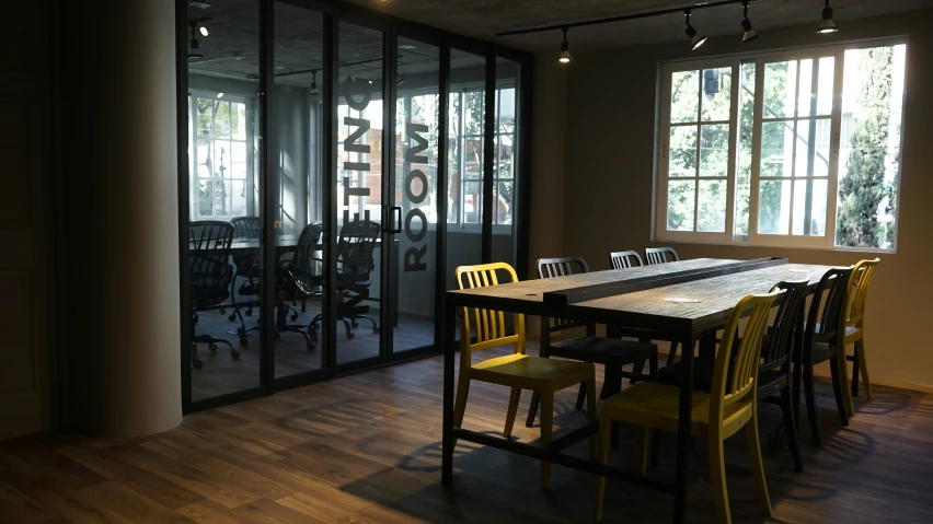 a modern glass walled office with wooden flooring and yellow chairs