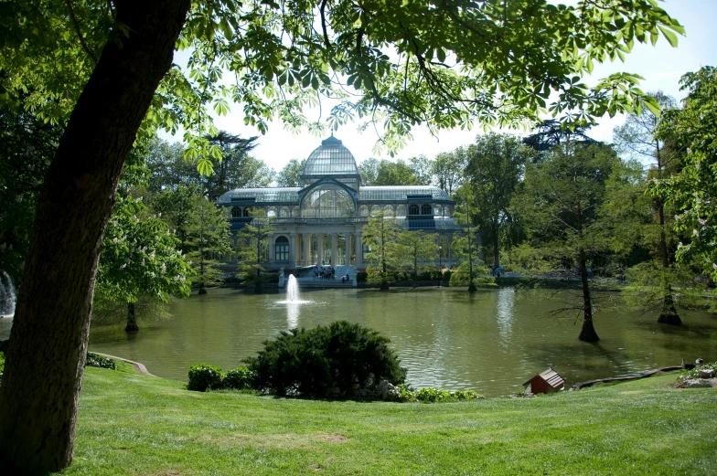 a pond and building with a statue in the distance