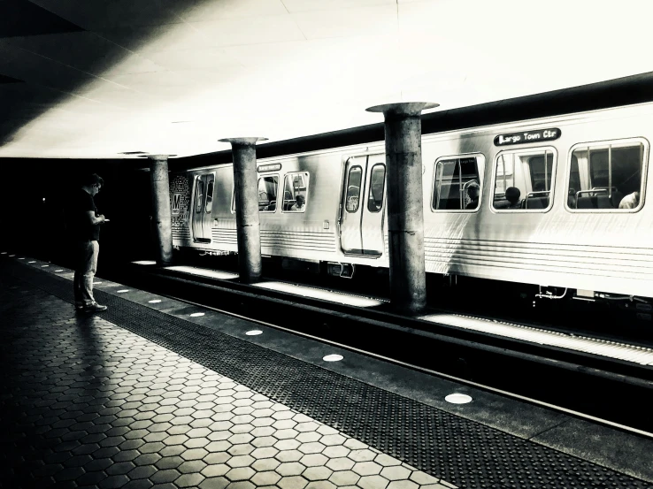 a train is passing by as a person is standing on a platform