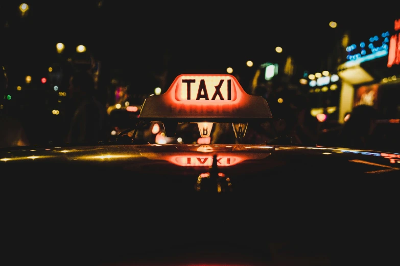 a taxi sign lit up at night and buildings reflecting in the water