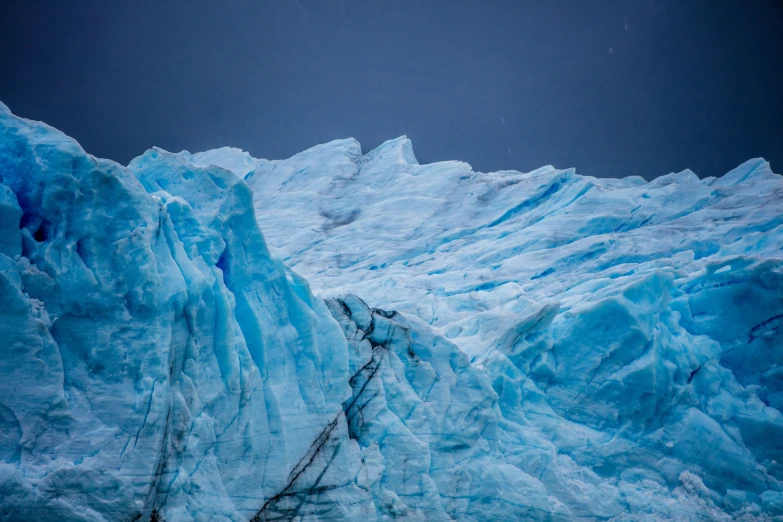 the side of an ice shelf in front of a cloudy sky