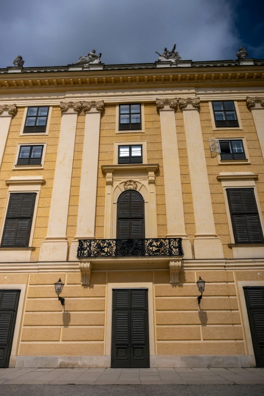 a tall building with windows and doors under a gray cloudy sky