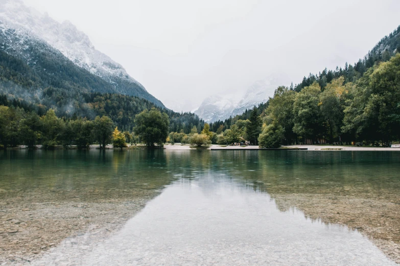 mountains are seen in the background while water and trees look calm