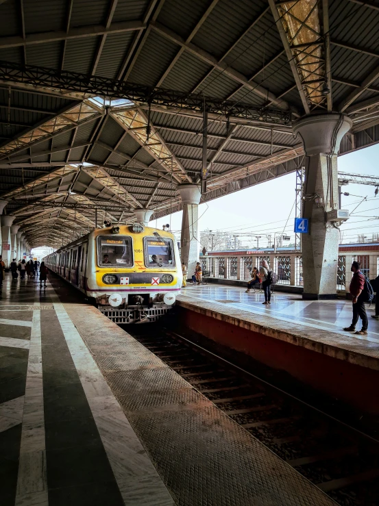 the yellow train is sitting idle in a station