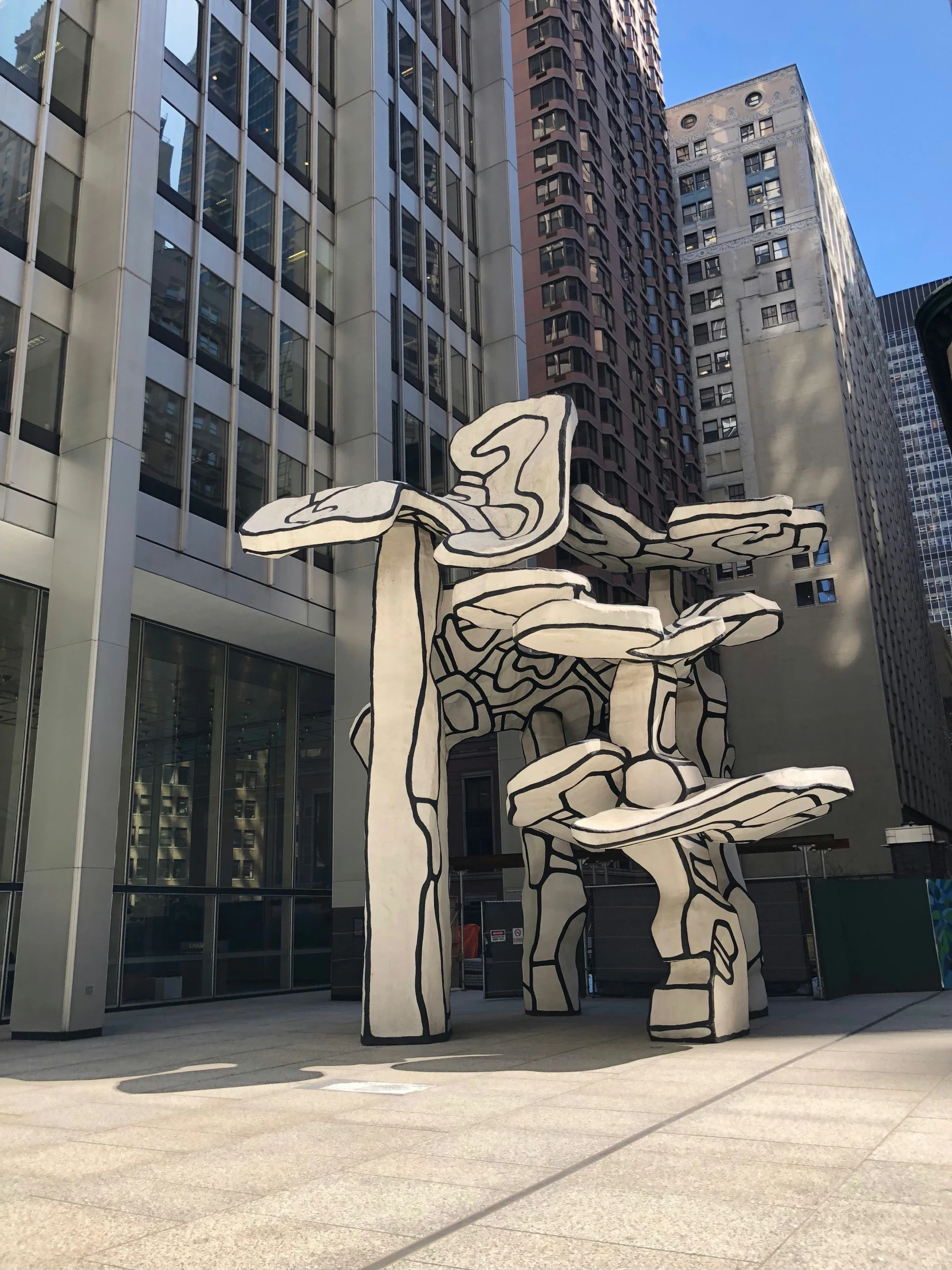 a large sculpture on the sidewalk in front of tall buildings