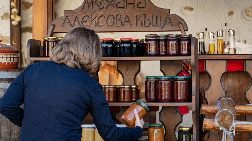 woman browsing jars on the shelf of an open shop