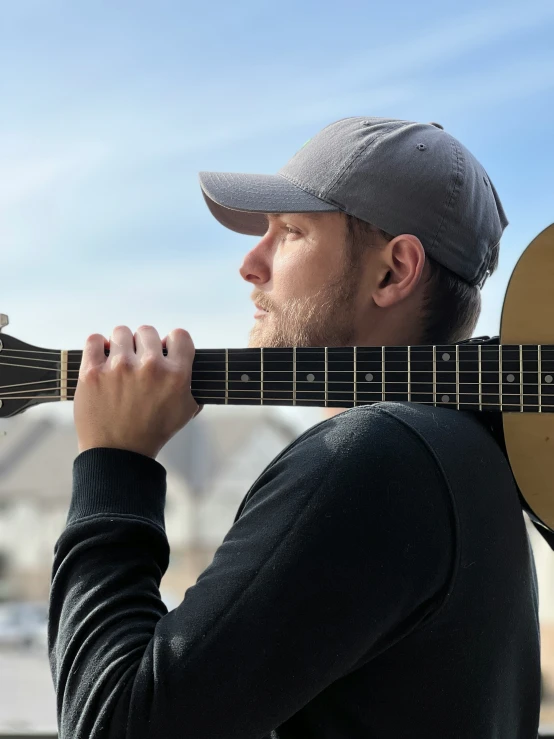 a man in gray hat holding a wooden guitar