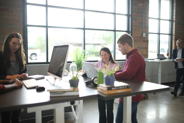 two women and one man using a computer in an office