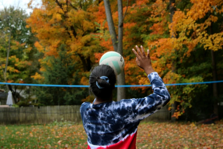 a young person standing in front of an orange and yellow tree