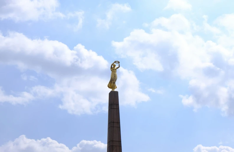 the tall yellow statue stands with its hand in her other hand