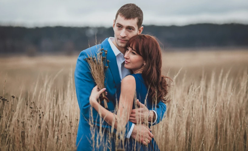 a man and woman that are standing in the grass