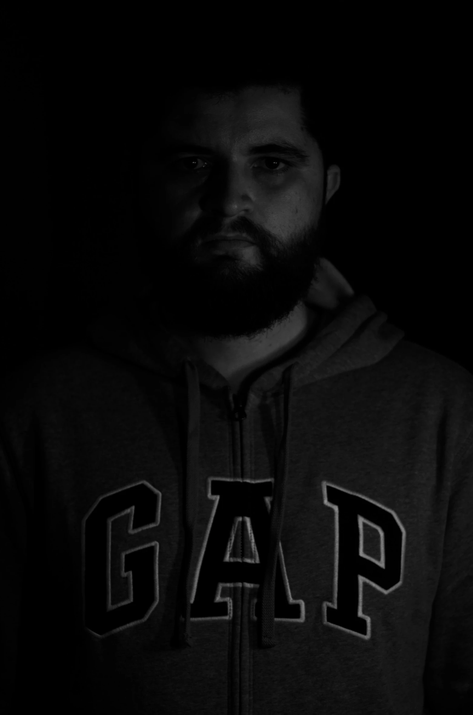a man standing in the dark wearing a hoodie