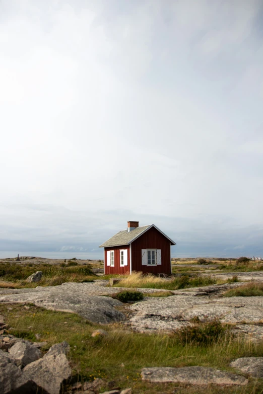 a small building sitting on a grassy field next to rocks