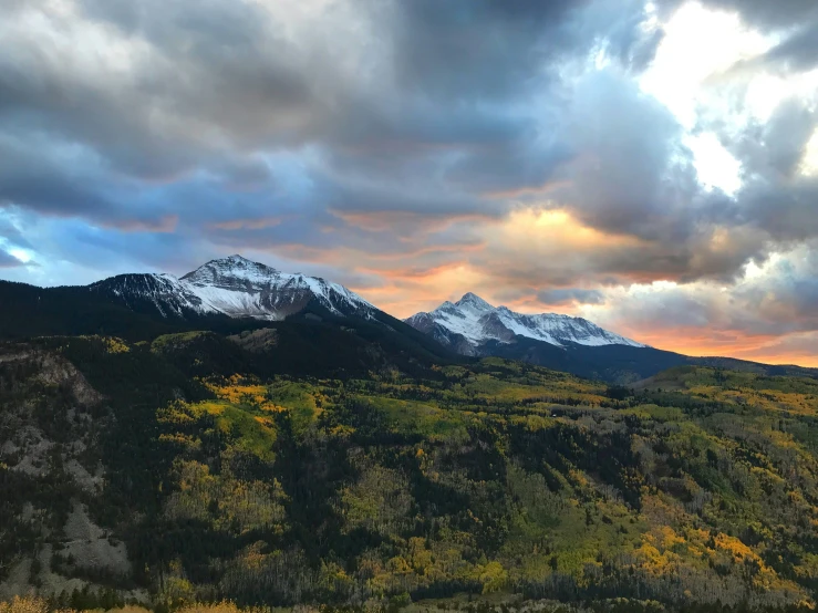 there is snow on the mountain top and the sun peeking through