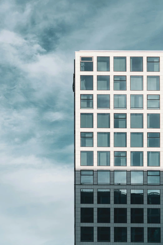 a tall building with large windows near a cloudy sky