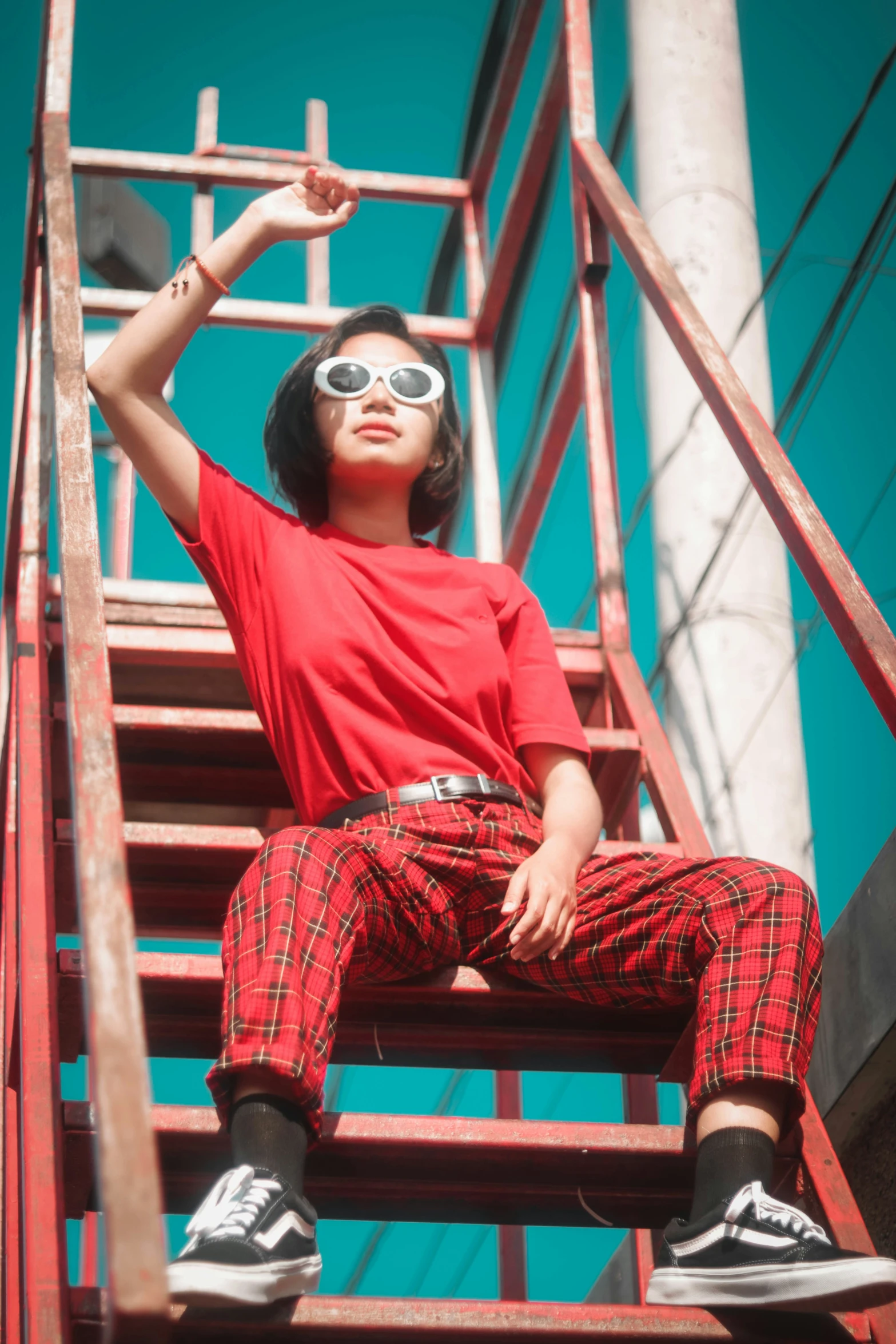 a young lady poses for a po while sitting on a fire escape ladder