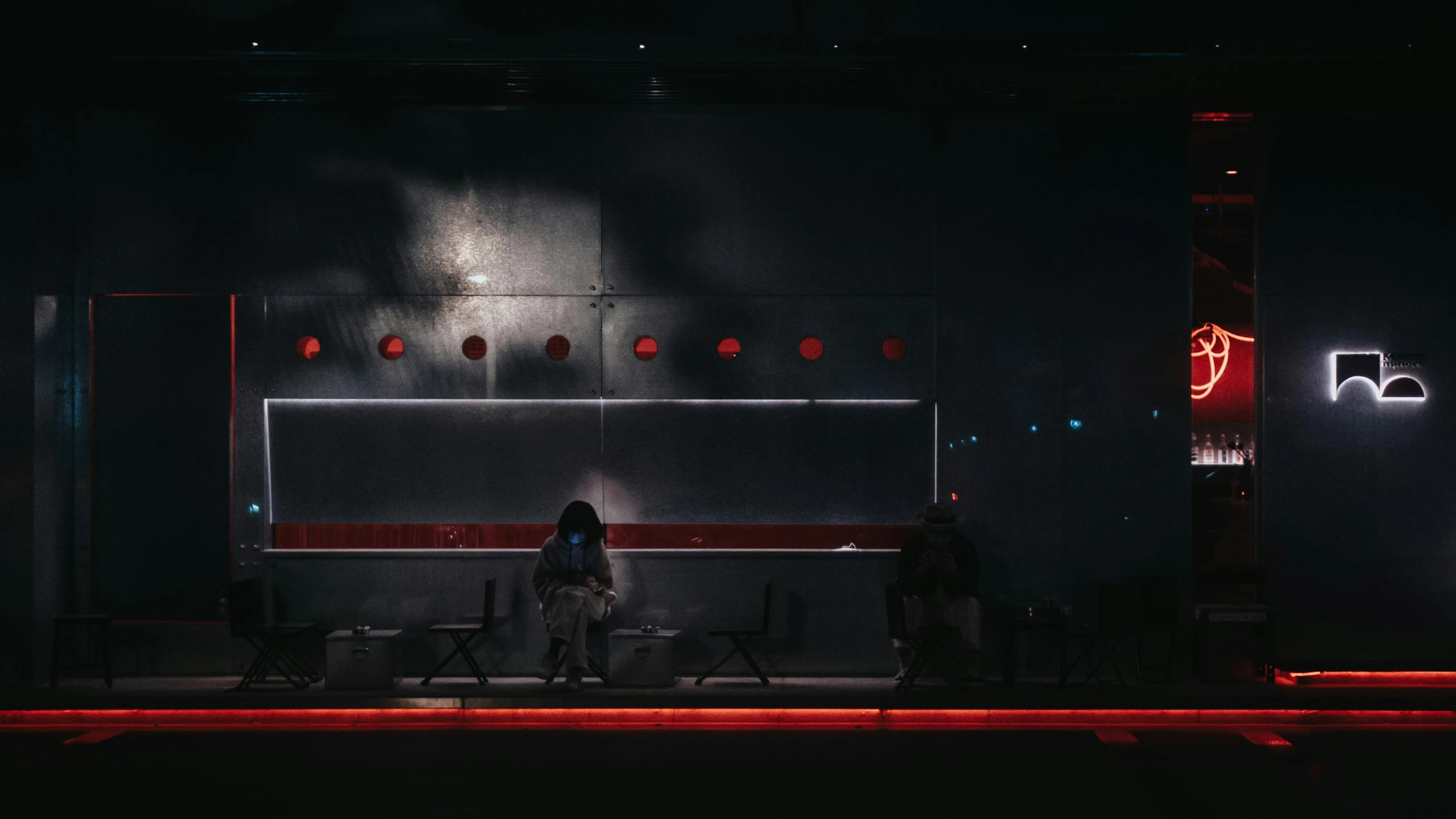 a woman sits on a bench in a darkened room