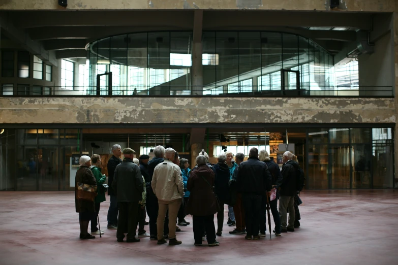 people gathered outside in front of a building under glass