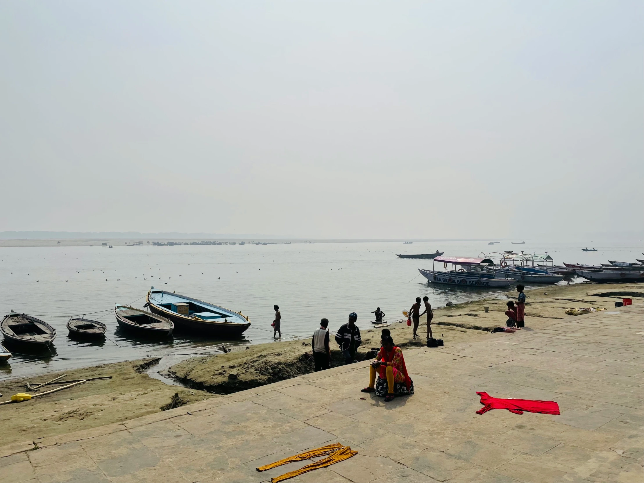 group of people stand on the beach by boats