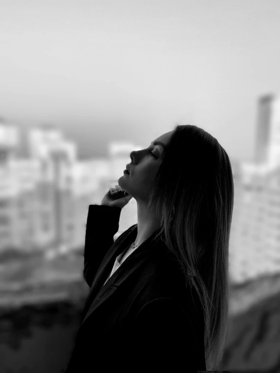 a woman talking on a phone next to some tall buildings