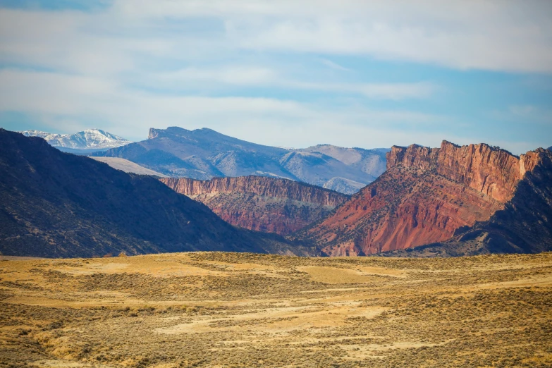 mountains and fields with a single black horse standing in the middle