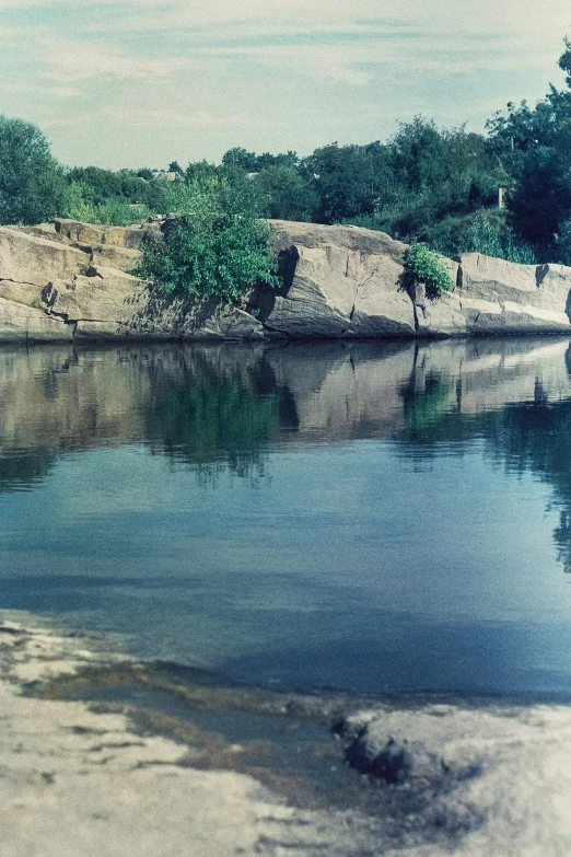 the river is blue with clear water, trees, and rocks