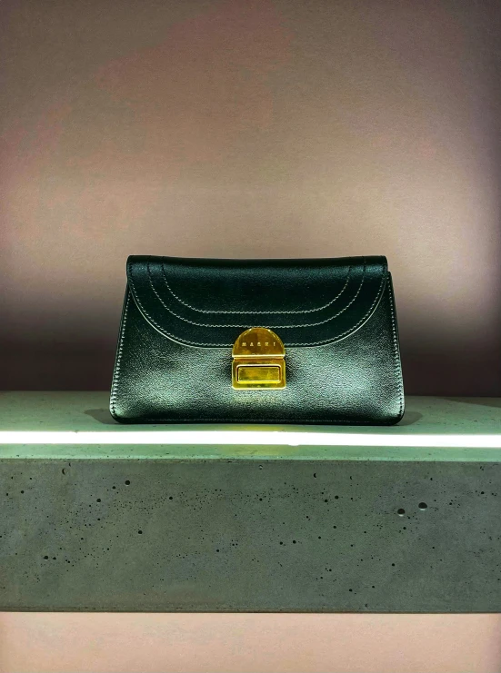 the black structured leather purse is held on top of the counter