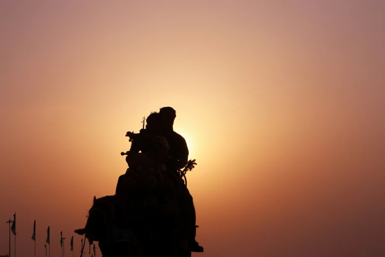 people riding elephants and watching the sun go down