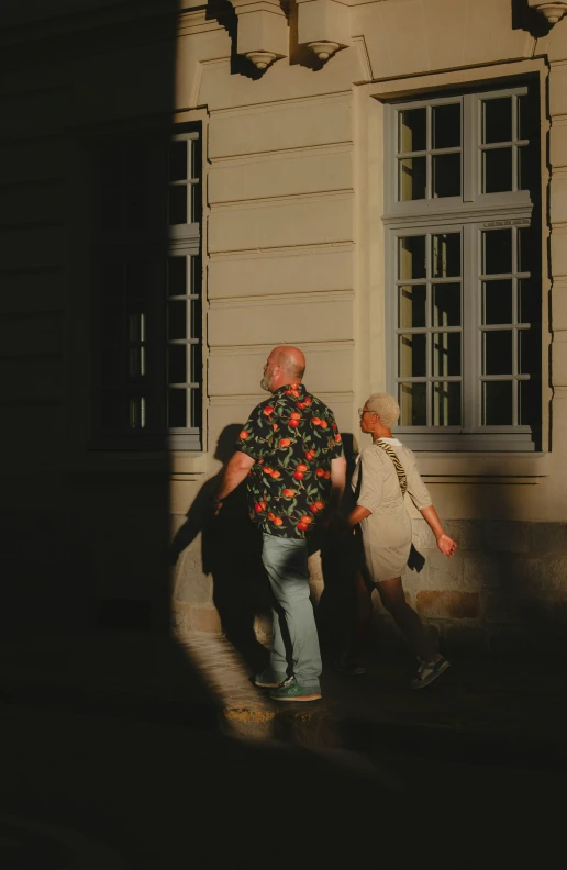 two people walk next to each other in front of a building