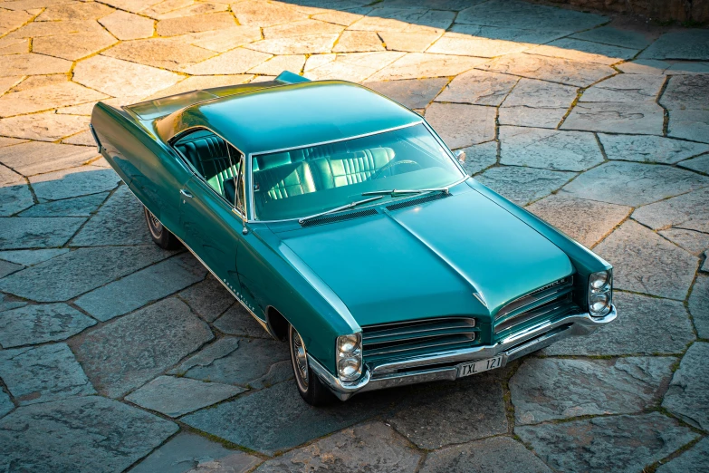 a green car parked on the pavement in the sun