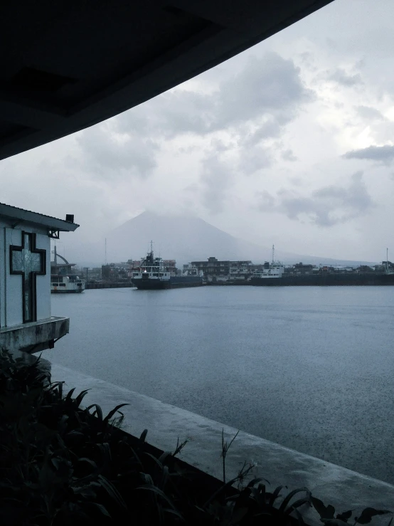 a body of water near a small building and hills