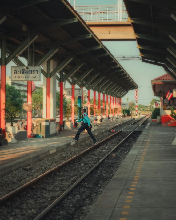 a man walking down train tracks near the platform