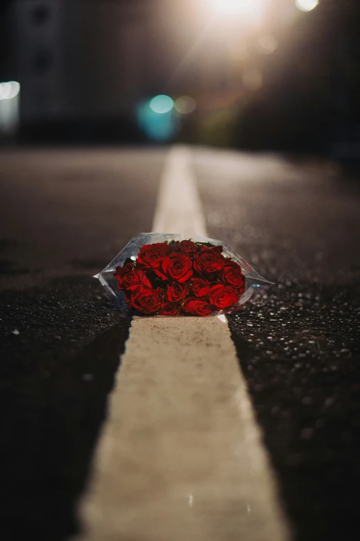 a bouquet of roses sits on a curb