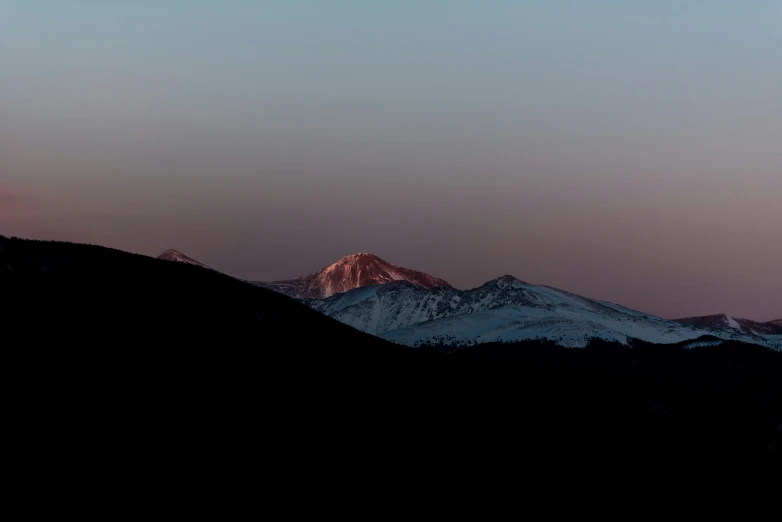 the sun rises on the snow covered mountains