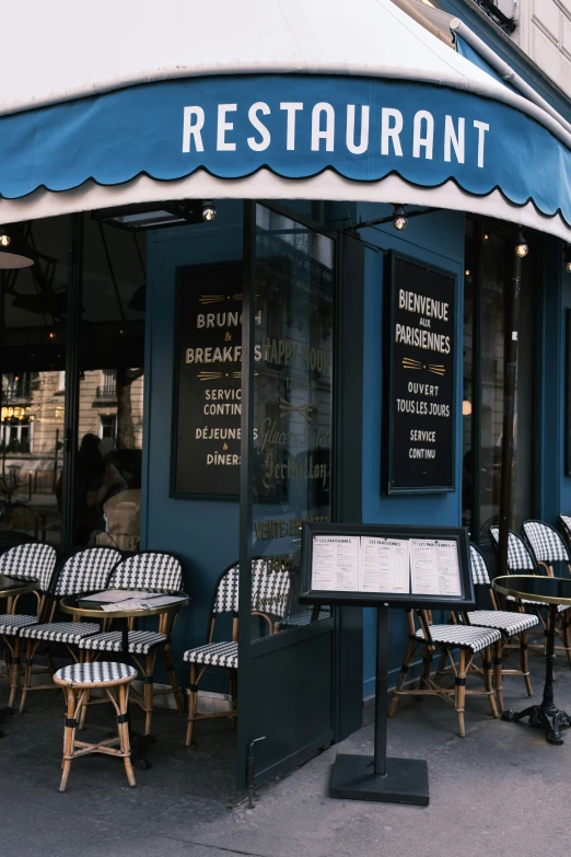 a restaurant sitting outside the doors has blue and white awning