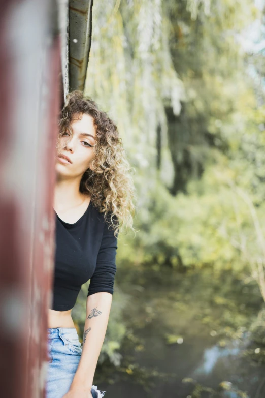 a woman poses leaning against a wall while looking down