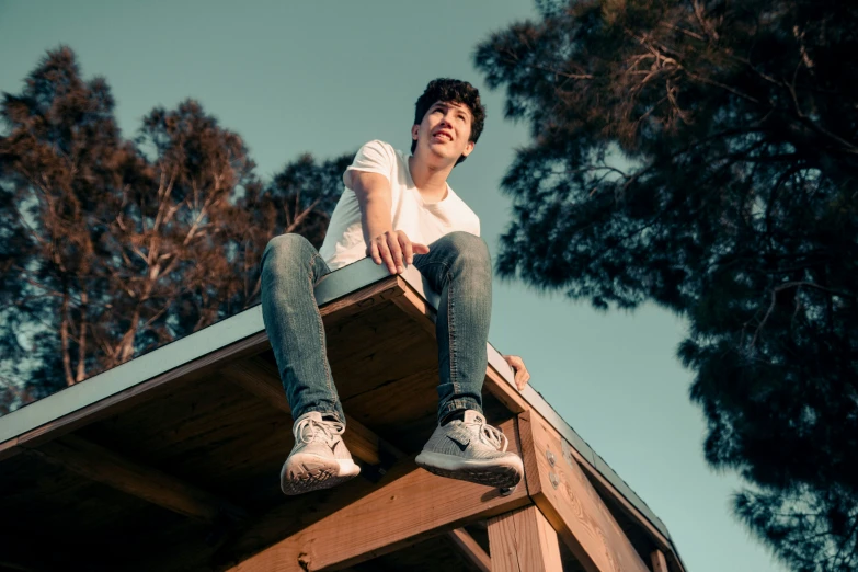 boy sitting on the roof of a house looking upward