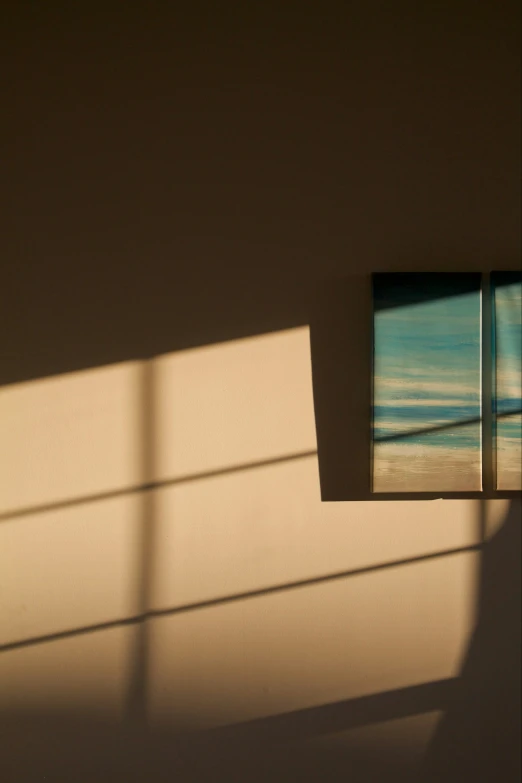 a wall with a frame over it and the shadow of a window