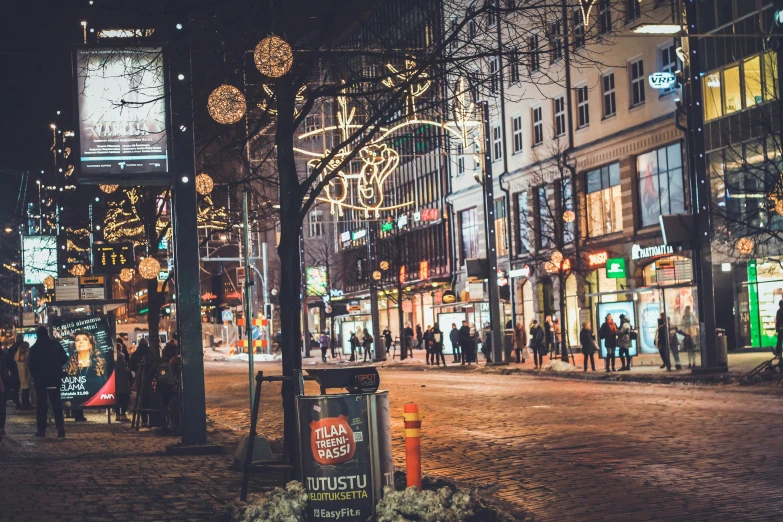 christmas decorations are hanging in the air and people walk on the street