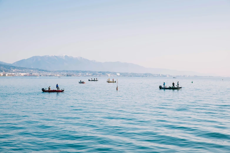 two boats in the water with three people out front