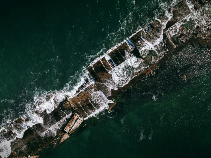an overhead view of the ocean with a boat stuck in the shore