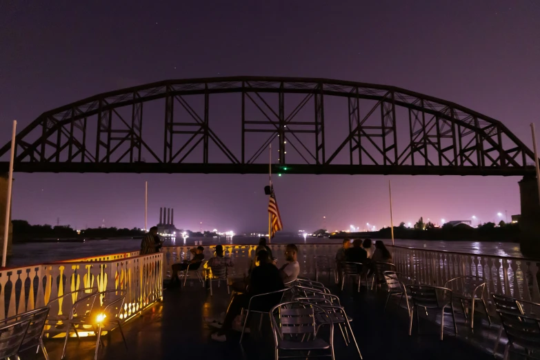 a couple of people sitting on a dock at night