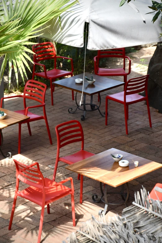 a variety of outdoor tables and chairs with red metal bases