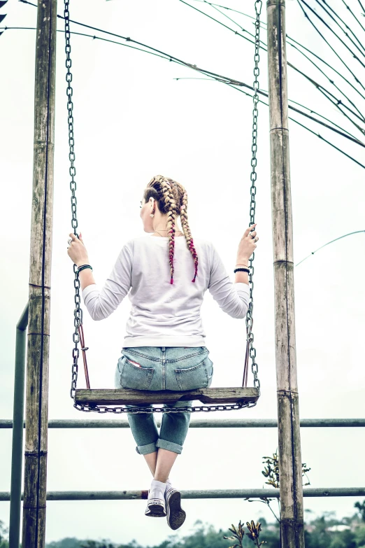 a girl sitting on a swinging frame outside